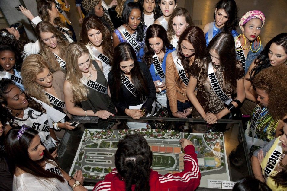 Candidates for the Miss Universe 2011 competition stand around a model of a stadium during a visit to the Futbol Soccer Museum in Sao Paulo