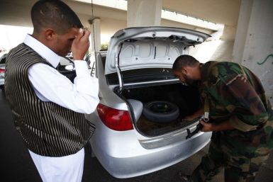 An anti-Gaddafi fighter searches a car at a checkpoint near the airport in Tripoli