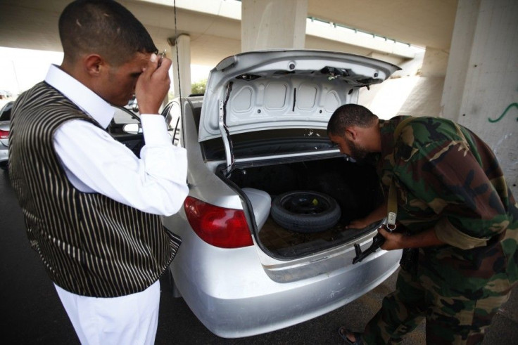 An anti-Gaddafi fighter searches a car at a checkpoint near the airport in Tripoli