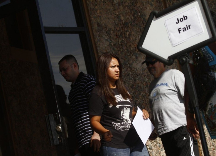 A woman exits a job fair at the Phoenix Workforce Connection as others wait to enter in Phoenix