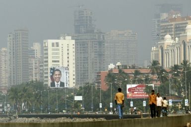 Residents walk in the city as a big banner of of U.S. President Barack Obama is pictured on a building, in Mumbai