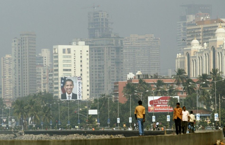Residents walk in the city as a big banner of of U.S. President Barack Obama is pictured on a building, in Mumbai