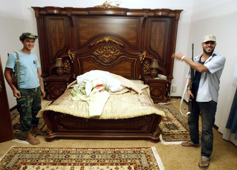 Anti-Gaddafi forces stand next to a bed at Muammar Gadhafis farm house near the town of Abu Grein some 138km 86 miles in the last remaining stronghold of Muammar Gaddafi, at the west of Sirte August 30, 2011