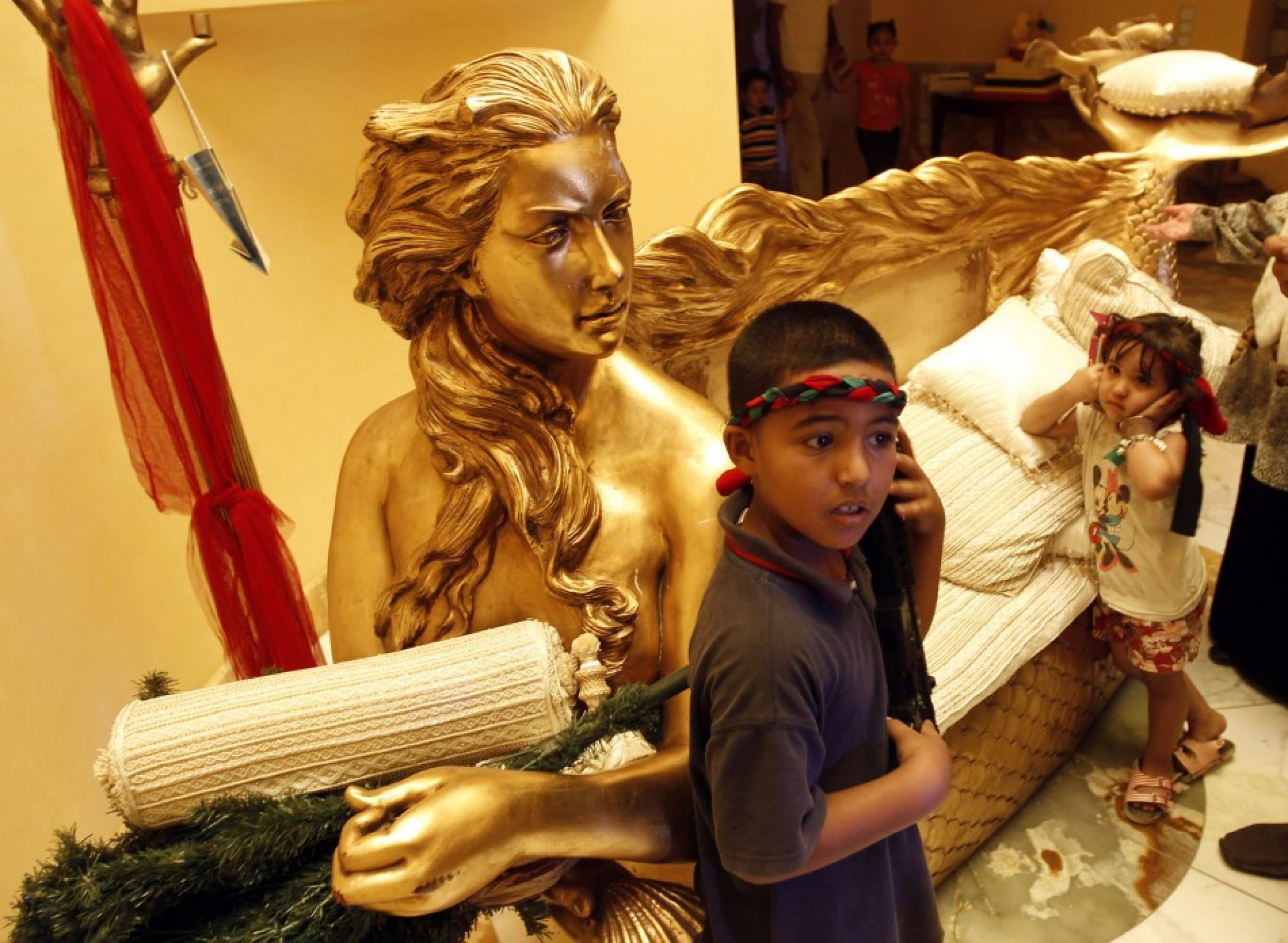 A boy stands next to a golden sofa with a statue of Aisha, the daughter of Libyan leader Muammar Gadhafi inside her house in Tripoli August 26, 2011