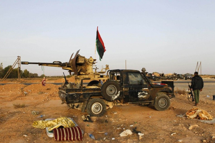 An anti-Gaddafi fighter walks next to a vehicle as he mans the last checkpoint to enter Bani Walid, currently held by pro-Gaddafi forces, in south east Tripoli