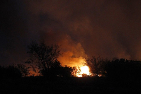 Flames and smoke rise from above the trees as a wildfire burns near Possum Kingdom Lake