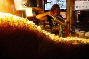 Cailynn Williams, 17, fills a bag of popcorn for a customer at the New Strand Theater in West Liberty