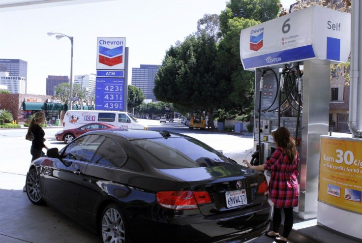 A woman stands at a gas pump at a Chevron gasoline station in Los Angeles