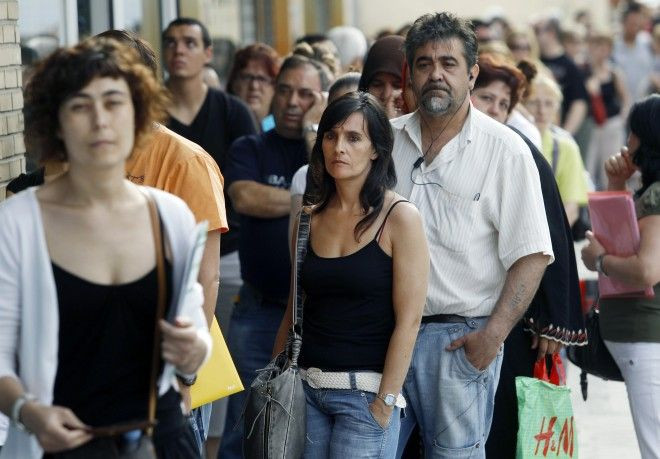 People wait in line to enter a government job centre in Madrid