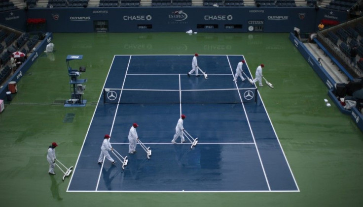 Court workers remove water from the playing surface of Arthur Ashe Stadium after rain delayed competition in the U.S. Open tennis tournament in New York