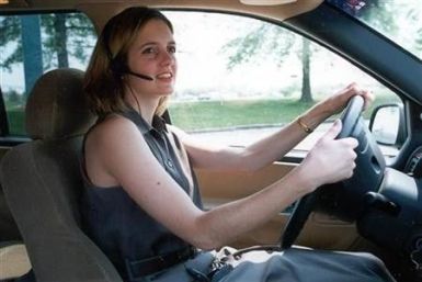 An unidentified woman uses a &#039;&#039;hands-free&#039;&#039; headset to make her driving