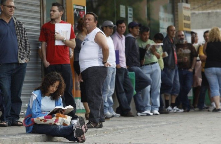 People wait in line to enter a government job centre in Madrid