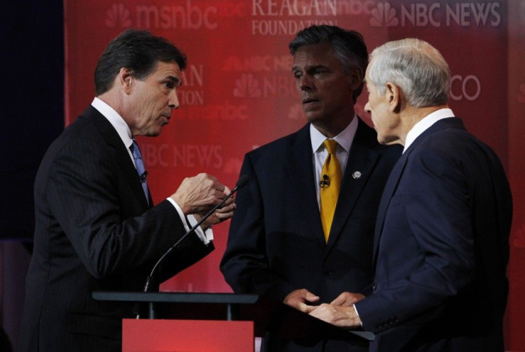 Republican presidential candidates Perry, Paul and Huntsman talk during a break in the presidential primary debate