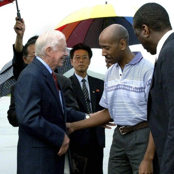Former U.S. President Jimmy Carter (L) and Aijalon Mahli Gomes (2nd R) talk before they leave Sunan airport in Pyongyang August 27, 2010.