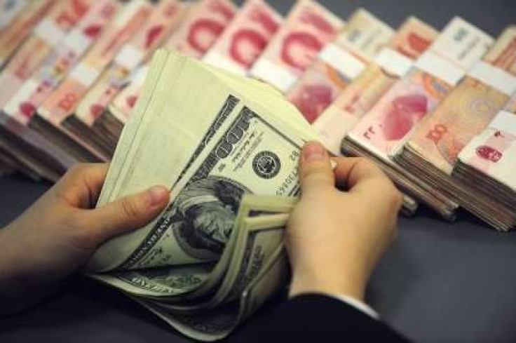 An employee counts U.S. currency near renminbi notes at a bank in Hefei, Anhui province