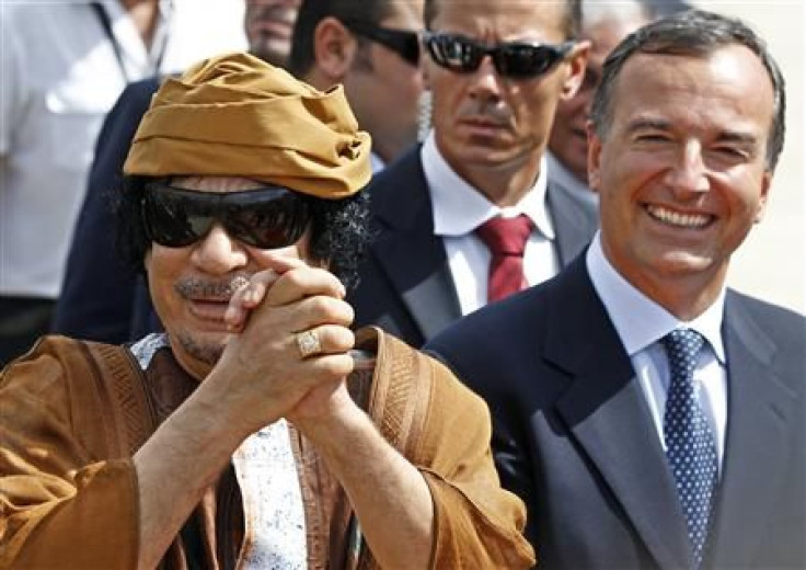 Libyan leader Gaddafi gestures next to Italian Foreign Minister Frattini at the Ciampino airport in Rome
