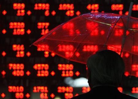 A businessman looks at share prices on an electronic board outside a brokerage in Tokyo