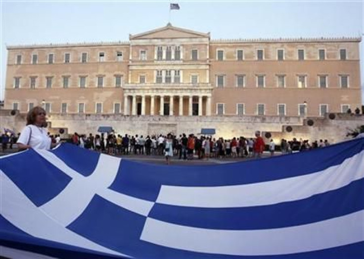 Protester holds giant Greek national flag in front of parliament building during rallyn in Athens&#039; Syntagma square