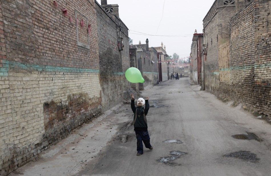 Wang Gengxiang, known as quotMasked Boyquot, plays with a balloon in an alley at Mijiazhuang village on the outskirts of Fenyang
