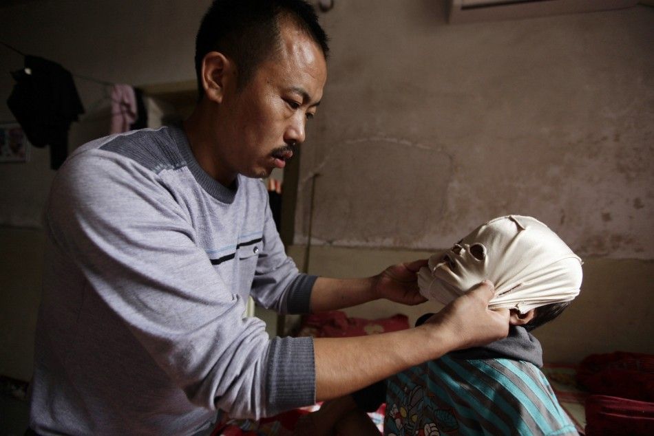 Wang Shouwu helps his son wear a mask