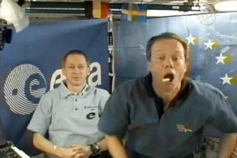European Space Agency astronaut Christer Fuglesang catches some food in his mouth as fellow ESA astronaut Frank De Winne looks on
