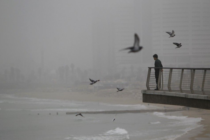 A man looks at the Mediterranean Sea on a foggy morning in Tel Aviv