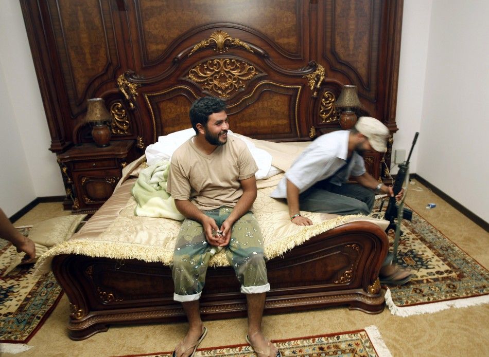 Anti-Gaddafi forces sit on a bed at Muammar Gaddafis farm house 