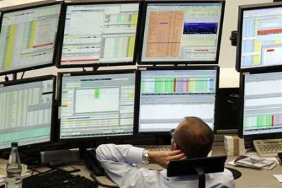 A trader is pictured at his desk in front of the DAX board at the Frankfurt stock exchange