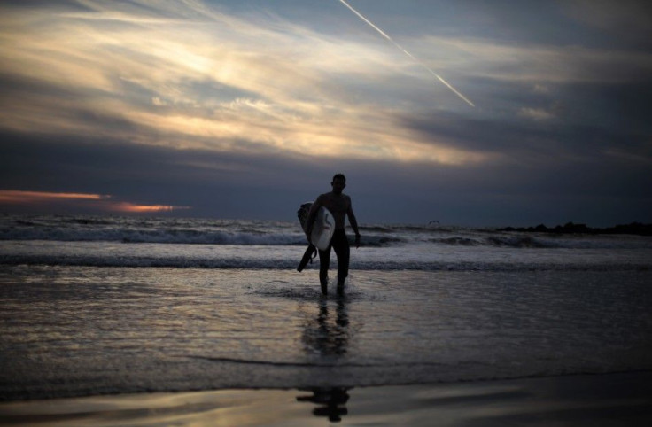 A surfer walks out of the ocean as the sun sets on New Year's Eve on Venice Beach in Los Angeles