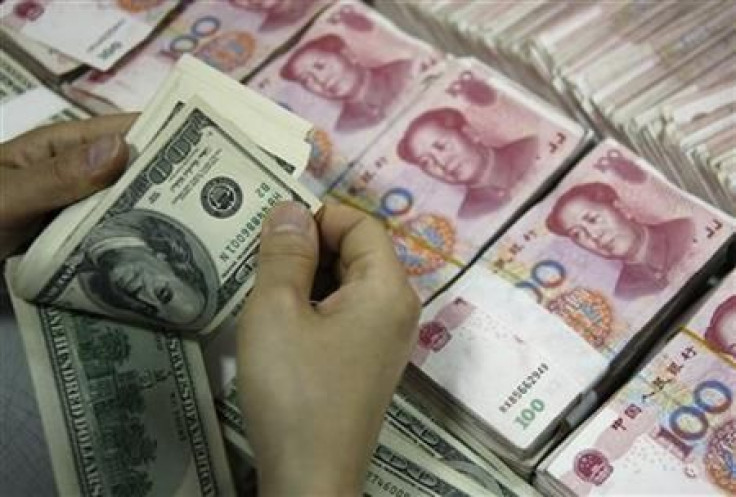 File photo of an employee counting U.S. dollar banknotes as yuan banknotes are seen at a branch of the Industrial and Commercial Bank of China in Huaibei
