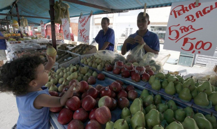 A child holds a pear in front of vendors at Feira Livre market on a streets of Vila Madalena neighbourhood in Sao Paulo