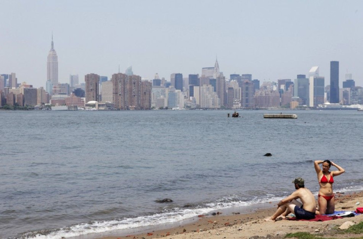 A couple relaxes on a small beach during a hot summer day at a park in the Brooklyn borough of New York