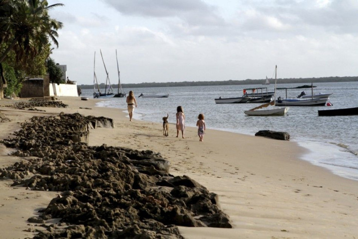 Tourists walk along the beach at Kiwayu Safari Village resort, north of Lamu