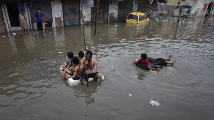 Residents use styrofoam and an inner tube to float down a flooded street in Karachi