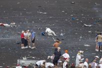 Debris are scattered as people rush to help injured spectators following the crash of a vintage World War Two P-51 Mustang fighter plane near the grandstand at the Reno Air Races in Reno Nevada