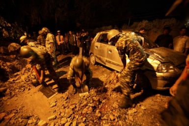Members of the Nepalese army clear stones around a damaged car after the wall surrounding the British Embassy collapsed on top of the car that was passing by in Kathmandu 