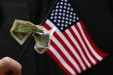 A student graduating from Harvard&#039;s Business School holds a U.S. flag with a dollar bill tied to it during the 357th Commencement Exercises at Harvard University in Cambridge
