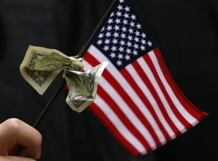 A student graduating from Harvard&#039;s Business School holds a U.S. flag with a dollar bill tied to it during the 357th Commencement Exercises at Harvard University in Cambridge