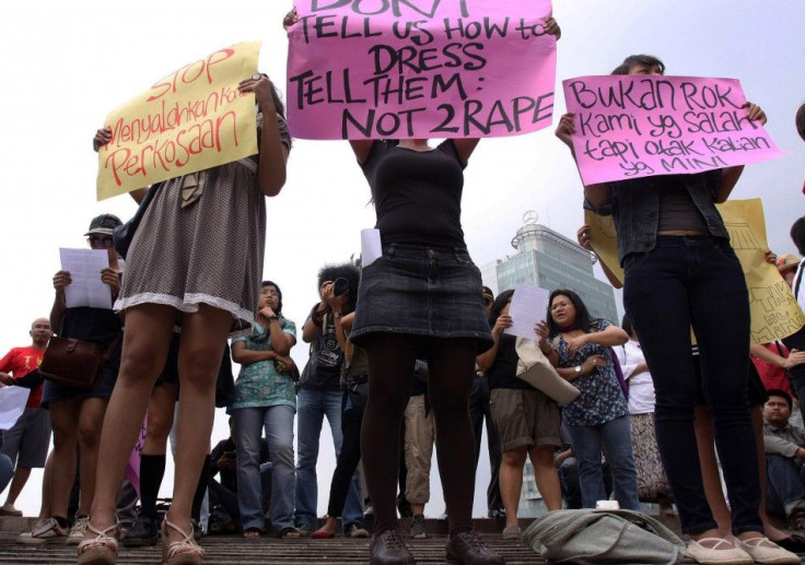 Women wearing miniskirts and tight leggings hold posters to protest against the idea that provocatively dressed women are to blame for sexual assaults, in Jakarta