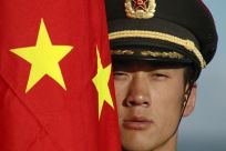 A Chinese soldier stands next to China's national flag