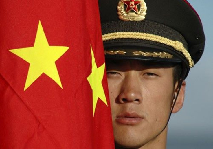 A Chinese soldier stands next to China's national flag