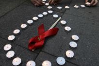 Activists distribute red ribbons and light up candles as they commemorate victims of the Human Immunodeficiency Virus, or HIV, during a flashmob in St.Petersburg