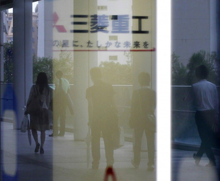 Logo of Mitsubishi Heavy Industries Ltd. is seen as people are reflected on a window at the company headquarters in Tokyo