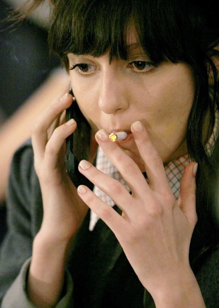 A model smokes a cigarette and talks on her cellular phone backstage at the BCBG Max Azria fall fashion show during New York Fashion Week