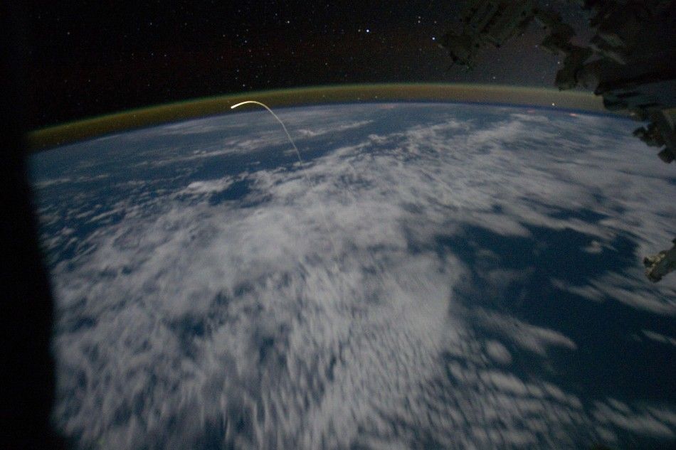 This unprecedented view of the space shuttle Atlantis, appearing like a bean sprout against clouds and city lights shows the shuttle on its way home as photographed by the Expedition 28 crew