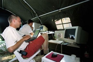 Dutchmen Jacco van Koll (L) and Luc Janssen work on their computers as they enjoy the shade of their tent during the international open-air Hacking in Progress conference in Almere, August 8.