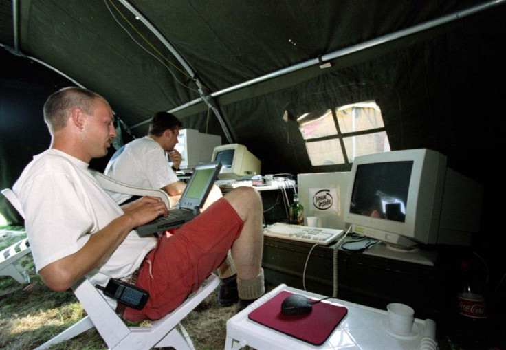 Dutchmen Jacco van Koll (L) and Luc Janssen work on their computers as they enjoy the shade of their tent during the international open-air Hacking in Progress conference in Almere, August 8.