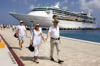 Tourists walk beside Royal Caribbean's cruise ship ?Enchantment of the Seas? after they arrive in Cozumel