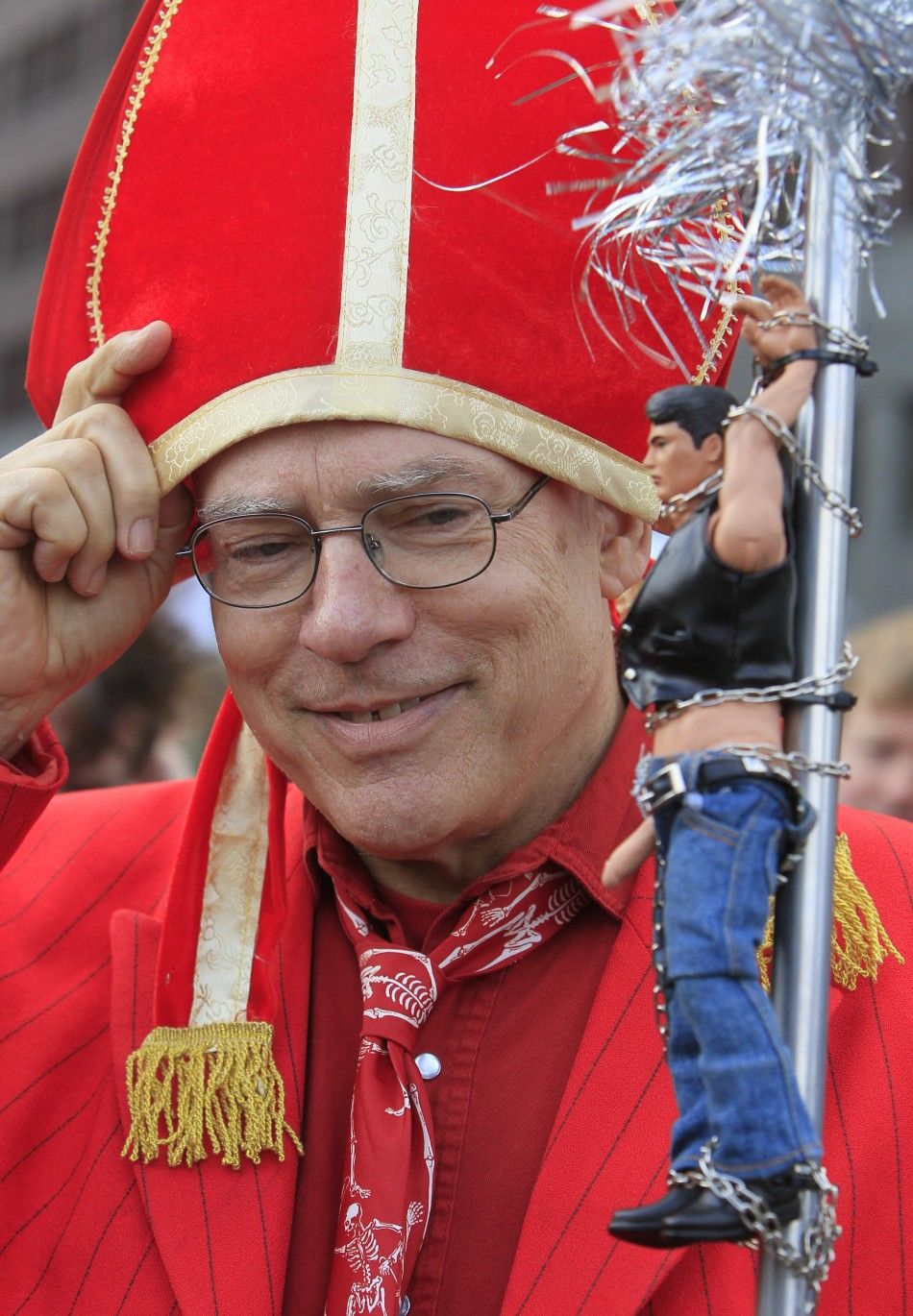A demonstrator opposing the visit of Pope Benedict XVI dresses as a Cardinal and holds an action figure doll during a protest at Potsdamer Platz in Berlin