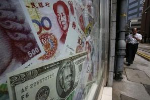 Photos of yuan and U.S. dollar banknotes are displayed at a money exchange in Hong Kong